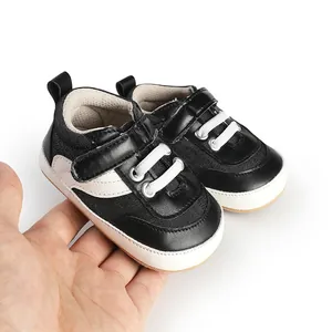 Detail view of black and white baby toddler shoes with velcro strap held in hand