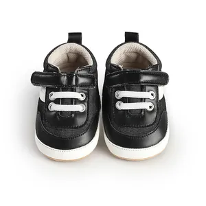 Top view of black and white infant walking shoes with velcro strap and white laces