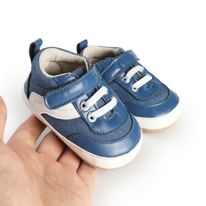 Close-up detail of blue and white baby canvas pre-walker sneakers held in hand for scale