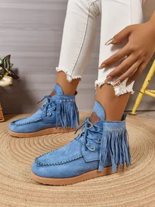 Detail van blauwe suède enkellaarsjes met franjes, studs en mocassinstiksels