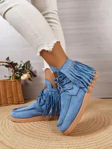 Detailweergave van blauwe suède laarzen met franjes kwastjes en gouden stud accenten
