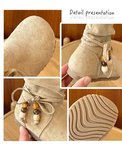 Dettaglio ravvicinato di stivali beige retrò per bambina con fiocco e perline.