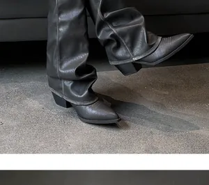 Detailed view of grey pointed-toe slouchy pant boots with chunky heels on concrete