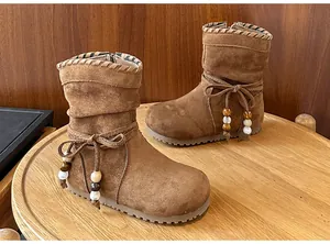 Dettaglio di stivali per bambina in camoscio marrone con fiocco e perline decorative