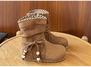 Dettaglio stivali bambina in camoscio marrone con fiocco e decorazioni di perline.