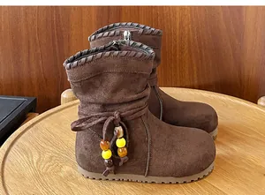 Dettaglio di stivali marroni retrò per bambina con perline colorate e fiocco.