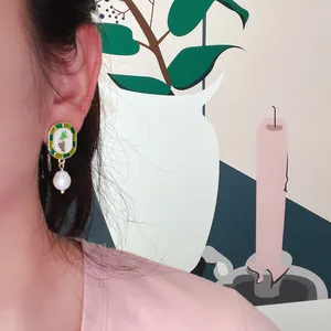 Détail de boucles d'oreilles vintage en émail de raisin avec perle baroque.