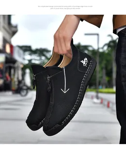Close-up of men's black leather boots featuring hand-stitched details and side zipper.