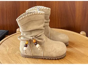 Dettaglio degli stivali in pelle scamosciata beige per bambina con fiocco e perline decorative