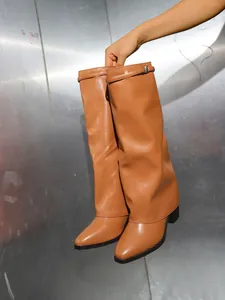 Detailopname van tan vouwlaarzen met een dikke hak en een elegante spitse neus.
