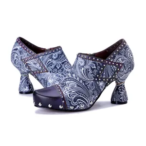 Detailed side view of leather high heels with blue paisley print and silver studs.