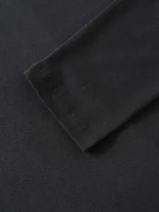 Dettaglio macro della doppia cucitura di qualità sul polsino di una t-shirt nera da uomo
