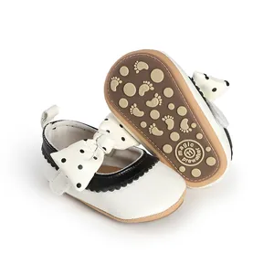 Close-up of white baby girl prewalker shoes with polka dot bow and non-slip sole