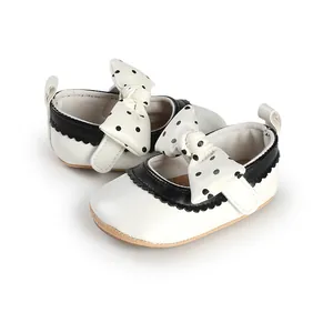 Detail view of white baby girl princess shoes with black polka dot bows.