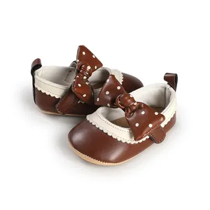 Brown baby girl princess shoes with polka dot bow detail and scalloped trim.