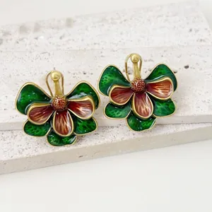 Vue détaillée de boucles d'oreilles vintage dorées avec fleurs en émail vert et rouge