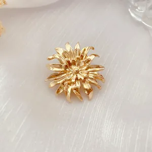 Nahaufnahme einer goldenen Chrysanthemen-Brosche im Vintage-Stil mit geschichteten Blüten.
