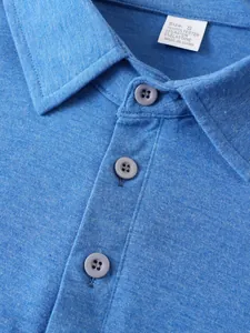 Dettaglio ravvicinato del colletto di una polo blu da uomo con etichetta