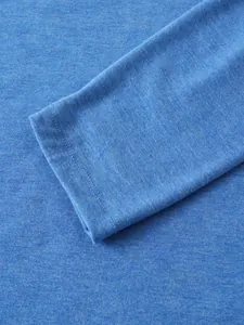 Dettaglio macro della trama del tessuto blu e del polsino di una polo a maniche lunghe.