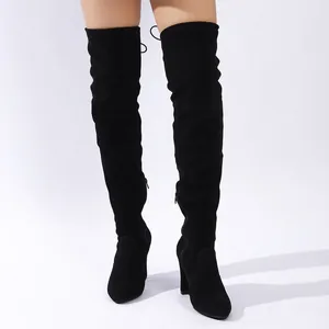 Elegante schwarze Overknee-Stiefel aus Wildleder mit Blockabsatz am Bein des Modells