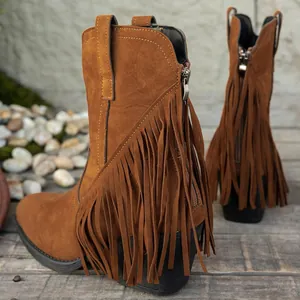 Primer plano detallado de botas western de ante marrón con flecos largos y modernos