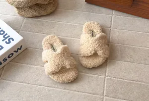 Dettaglio delle pantofole di peluche beige per bambini con fasce incrociate in ecopelliccia