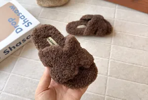 Dettaglio delle pantofole di peluche marroni per bambini con consistenza morbida