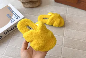 Dettaglio di morbide pantofole in peluche gialle per bambini con fasce incrociate