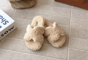 Primo piano di comode pantofole in sherpa beige per bambine con cinturini a incrocio