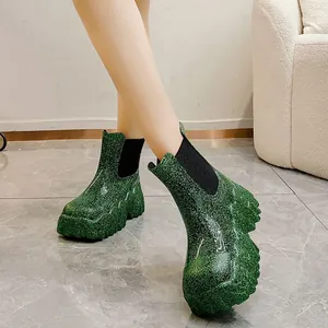 Detailopname van groene glitter platform enkellaarsjes met dikke zolen en elastiek.