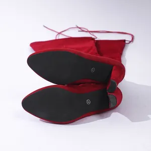 Detailansicht der schwarzen Sohlen und Blockabsätze roter Overknee-Stiefel aus Wildleder.