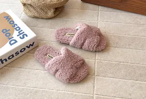 Vue rapprochée de pantoufles roses en peluche pour enfants avec sangles croisées souples
