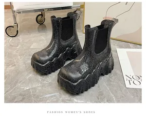 Gedetailleerd macro-overzicht van zwarte glitter enkelboots met dikke golvende zolen