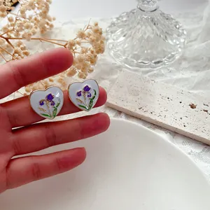 Dettaglio di orecchini vintage a cuore francesi con motivo a fiori di iris in smalto