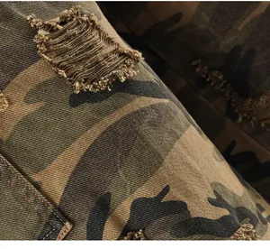 Detailed macro view of distressed stone-washed camouflage fabric showing ripped edge details