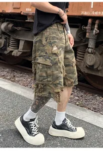 Detail of distressed camouflage cargo shorts with heavy industrial ripped effect.