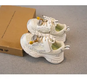 Detalle de zapatillas infantiles transpirables con parte superior de malla y dije de cara.