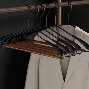Close-up detail of a luxury solid wood and black metal wide-shoulder hanger with white blazer