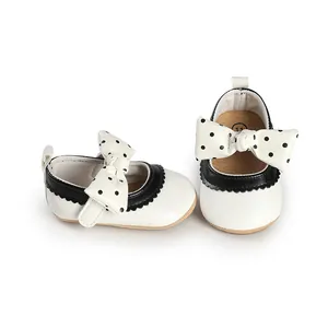 Close-up detail of white infant princess walking shoes with black polka-dot bow decoration