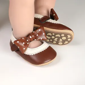 Detailed view of brown baby princess shoes featuring white polka dot bow and lace trim