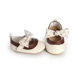 Detail view of cream infant Mary Jane shoes with brown polka dot bow decoration