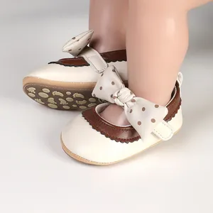 Close-up of cream and brown baby girl Mary Jane shoes with polka-dot bow detail