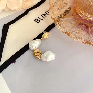 Primo piano di orecchini vintage francesi con perle barocche e dettagli dorati.