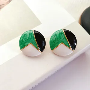 Detailed macro view of vintage round stud earrings with green, black, and white enamel.