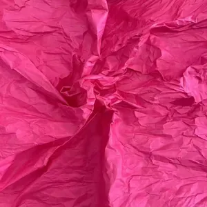 Detailed macro shot of bright magenta crumpled crepe paper texture for DIY craft projects