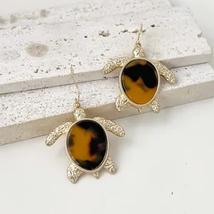 Detalle de pendientes de tortuga marina dorados con un patrón de carey vintage.