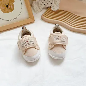 Macro view of beige infant walking shoes with a soft sole and a cute bear Velcro strap