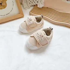 Close-up of beige baby walking shoes with a cute cartoon bear on the velcro strap.