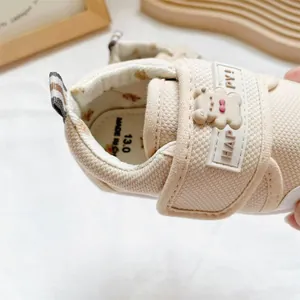 Detailed macro view of soft-sole beige baby walking shoes with cute 3D bear and HAPPY strap