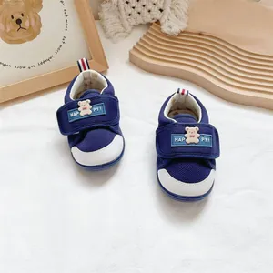 Close-up of navy blue baby walking shoes with cute bear decor and velcro strap